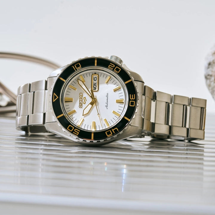 Seiko HDB004 white-dial automatic watch with stainless steel bracelet, styled on a reflective surface