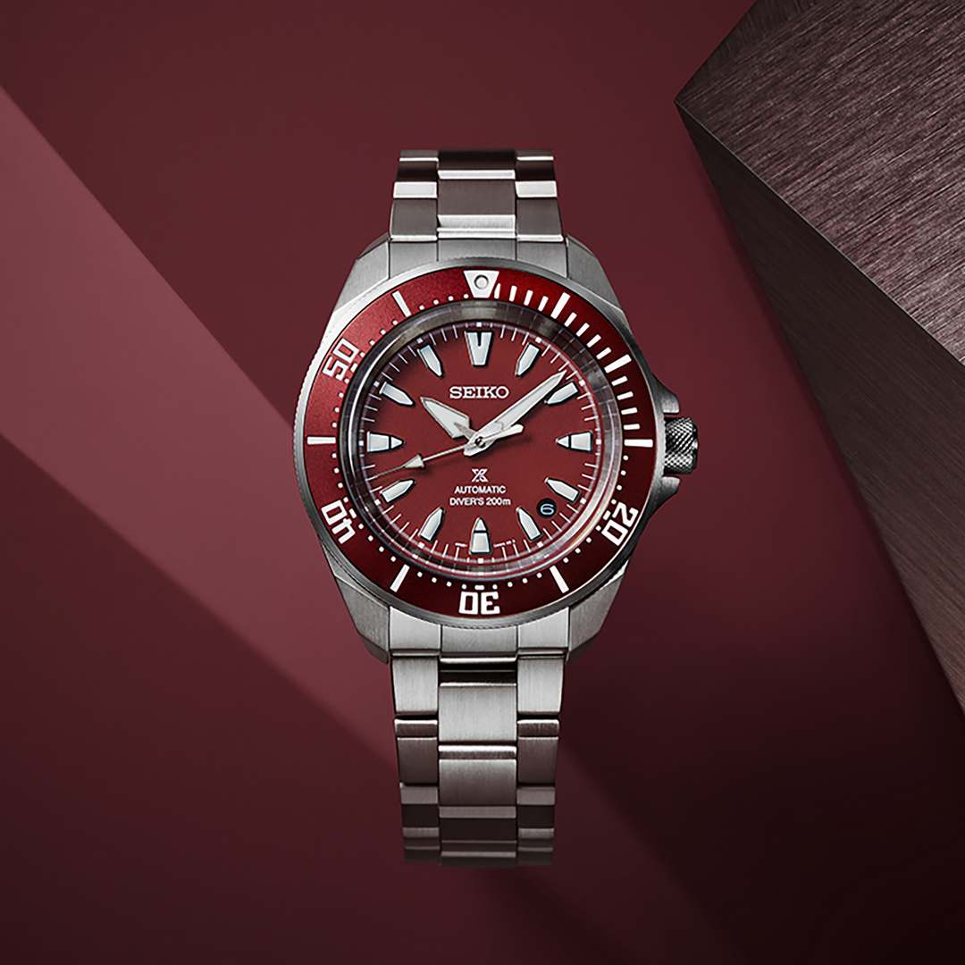 Seiko SRPL11 red-dial diver displayed against a red backdrop