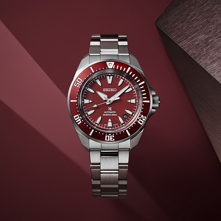 Seiko SRPL11 red-dial diver displayed against a red backdrop